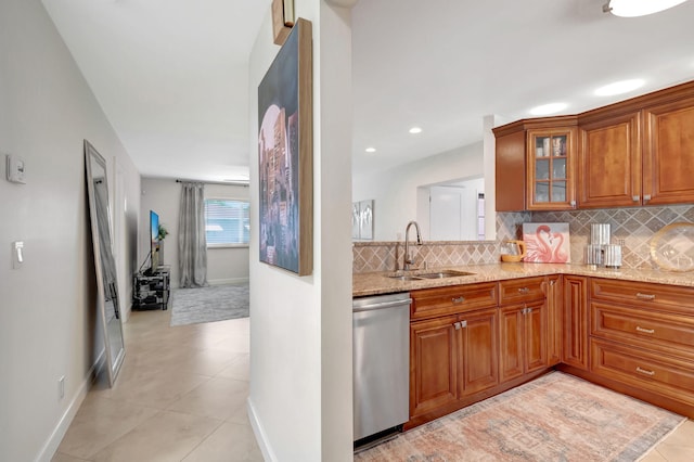 kitchen with dishwasher, backsplash, sink, light tile patterned flooring, and light stone counters