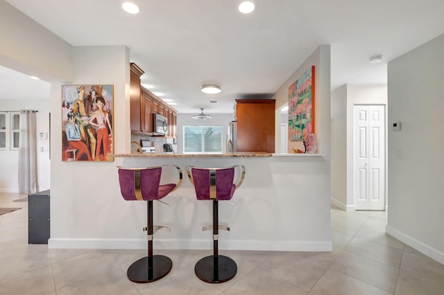 kitchen featuring kitchen peninsula, stainless steel appliances, and light tile patterned flooring