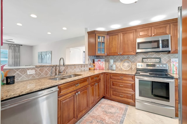 kitchen featuring sink, decorative backsplash, light tile patterned floors, appliances with stainless steel finishes, and light stone counters