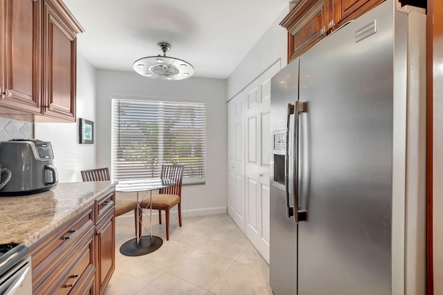 kitchen with decorative backsplash, light stone countertops, light tile patterned flooring, and appliances with stainless steel finishes