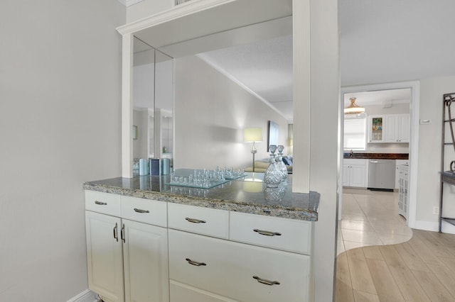 kitchen with light stone counters, dishwasher, white cabinets, and light wood-type flooring