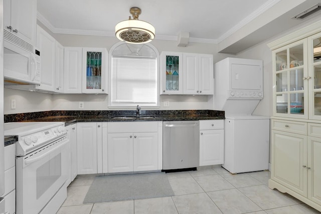 kitchen featuring white appliances, stacked washer and dryer, white cabinetry, and ornamental molding