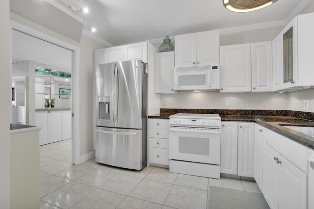 kitchen featuring dark stone counters, ornamental molding, white appliances, light tile patterned floors, and white cabinets