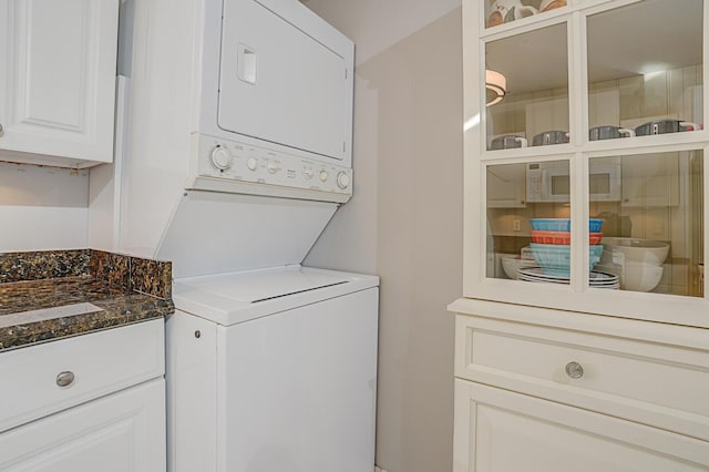 laundry room featuring cabinets and stacked washer and dryer