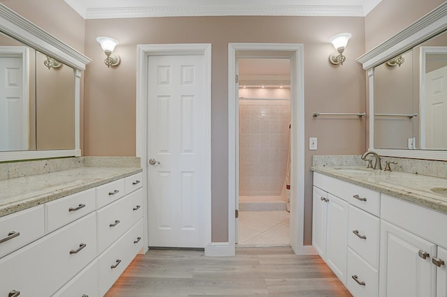 bathroom with hardwood / wood-style flooring, vanity, ornamental molding, and tiled shower