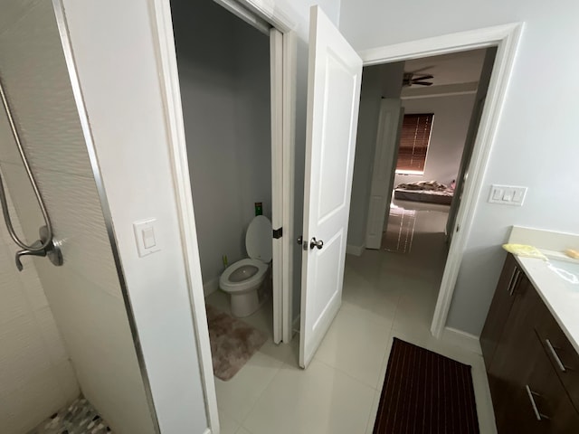 bathroom featuring ceiling fan, walk in shower, tile patterned flooring, toilet, and vanity