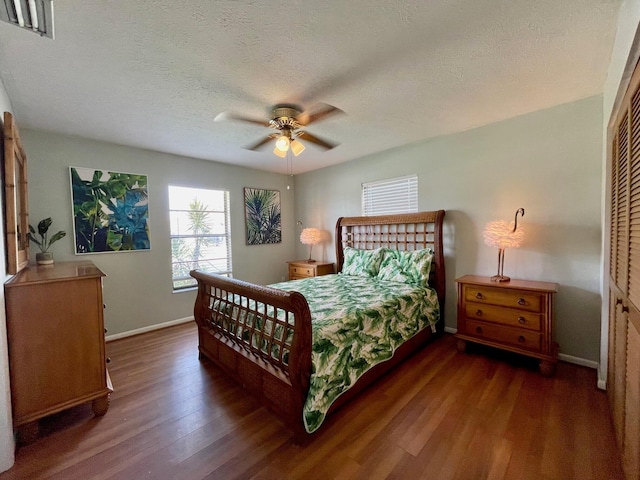 bedroom featuring a textured ceiling, dark hardwood / wood-style flooring, a closet, and ceiling fan