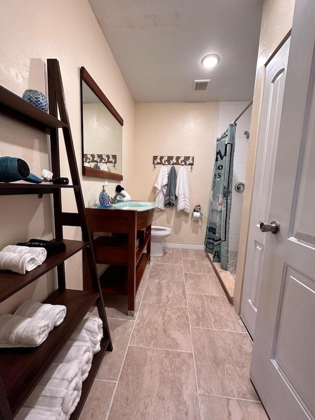 interior space featuring a shower with shower curtain, vanity, toilet, and tile patterned floors