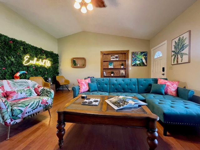 living room with hardwood / wood-style floors, built in features, ceiling fan, and lofted ceiling