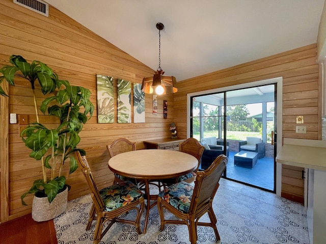 dining space featuring lofted ceiling and wooden walls