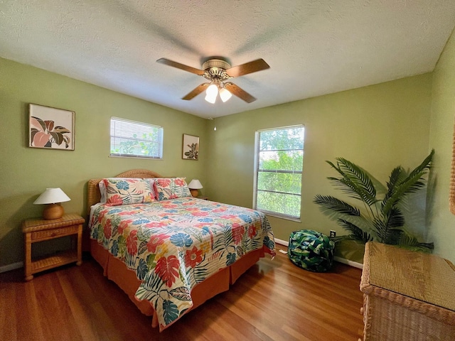 bedroom with ceiling fan, a textured ceiling, and hardwood / wood-style flooring