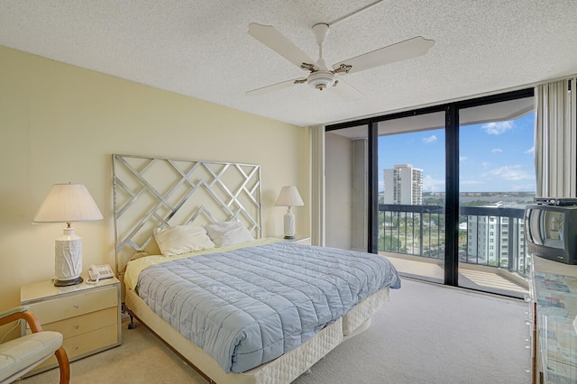 bedroom with floor to ceiling windows, ceiling fan, a textured ceiling, access to outside, and light carpet