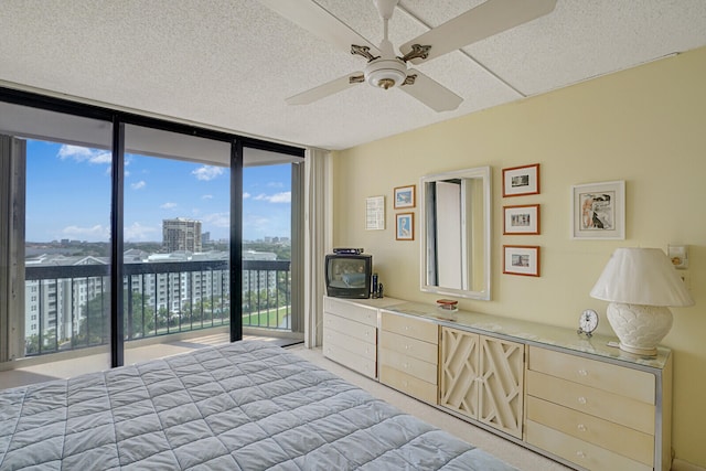 bedroom with access to exterior, expansive windows, and ceiling fan