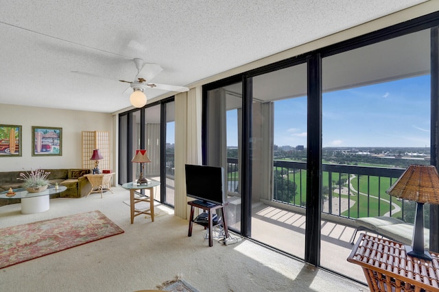 carpeted living room with ceiling fan, a wall of windows, and a textured ceiling