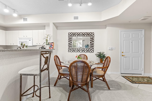 tiled dining space featuring a textured ceiling and track lighting