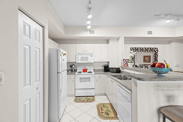 kitchen with kitchen peninsula, a kitchen breakfast bar, rail lighting, white appliances, and white cabinetry