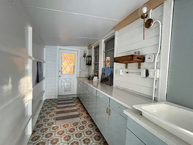 mudroom with dark tile patterned floors, vaulted ceiling, and sink