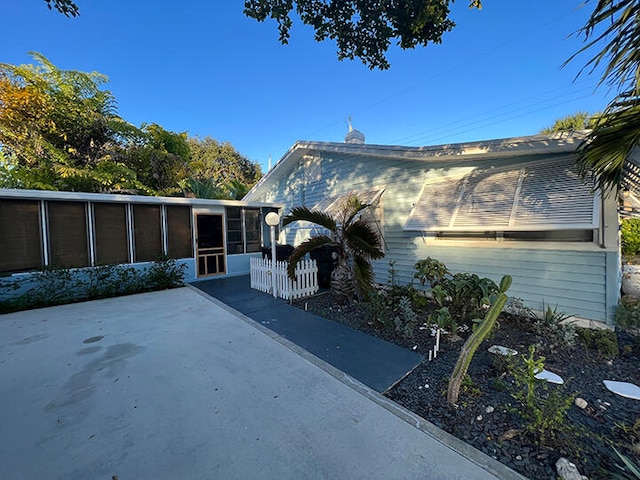 view of property exterior with a sunroom and a patio