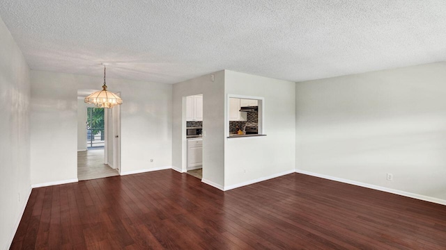 spare room with a textured ceiling, dark hardwood / wood-style flooring, and a notable chandelier