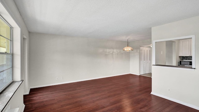 unfurnished living room with a textured ceiling and dark wood-type flooring