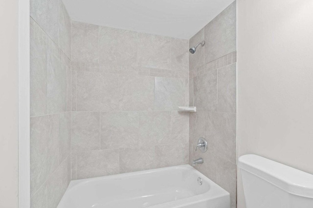 bathroom with toilet and tiled shower / bath