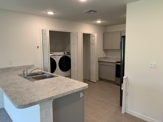 kitchen featuring gray cabinetry, independent washer and dryer, kitchen peninsula, and sink