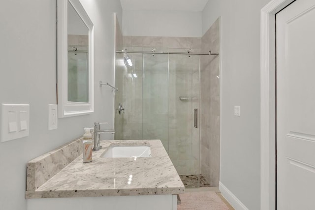 bathroom featuring a shower with door and vanity