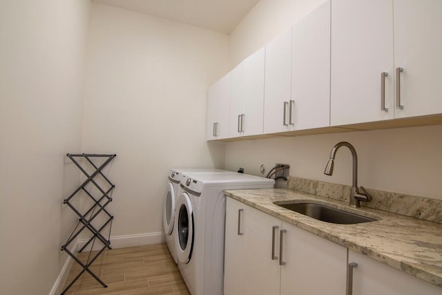 laundry room with cabinets, independent washer and dryer, sink, and light hardwood / wood-style flooring