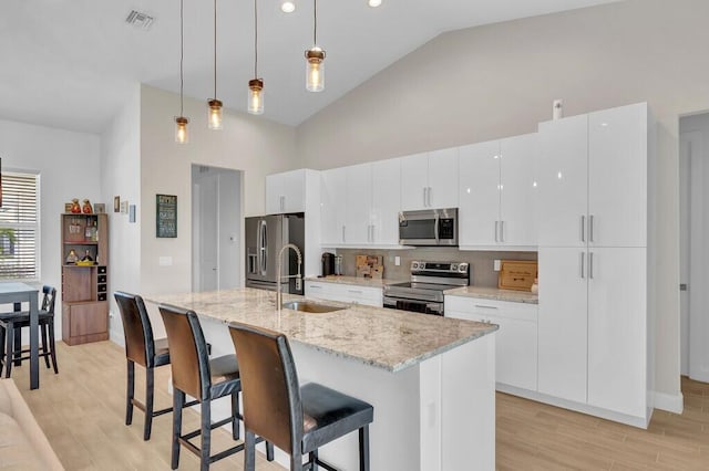 kitchen featuring pendant lighting, stainless steel appliances, a center island with sink, and sink