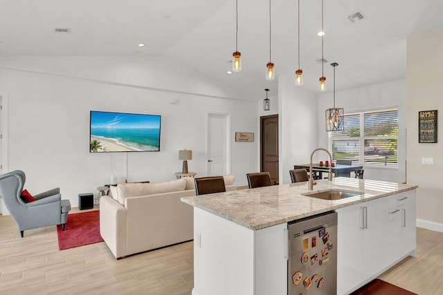 kitchen featuring pendant lighting, sink, white cabinetry, and an island with sink