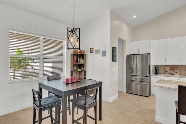 dining area with light hardwood / wood-style floors, lofted ceiling, and an inviting chandelier