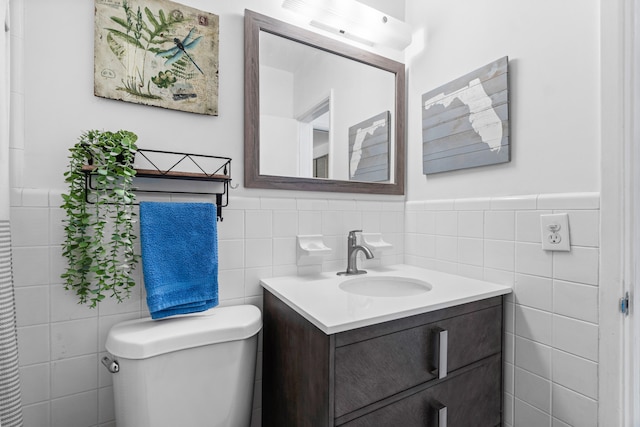 bathroom with vanity, toilet, and tile walls