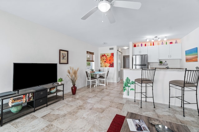 kitchen featuring ceiling fan, kitchen peninsula, stainless steel fridge, a breakfast bar, and white cabinets