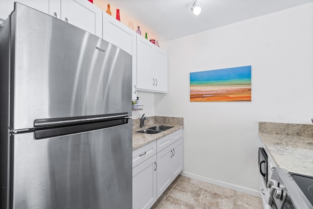 kitchen with white cabinets, light stone counters, sink, and appliances with stainless steel finishes