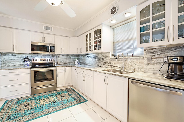 kitchen with light stone countertops, sink, light tile patterned floors, white cabinets, and appliances with stainless steel finishes