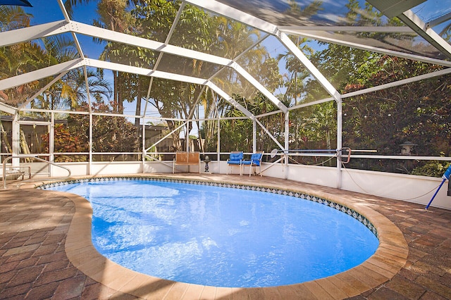 view of swimming pool featuring glass enclosure and a patio area