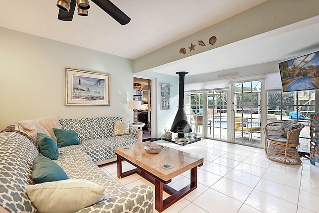 living room featuring a wood stove, ceiling fan, and light tile patterned floors