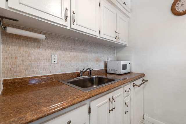 kitchen featuring tasteful backsplash, white cabinetry, and sink