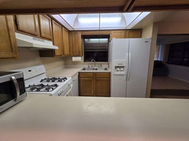 kitchen with beamed ceiling, white appliances, sink, and a skylight