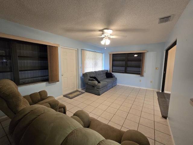 living room with visible vents, a ceiling fan, light tile patterned flooring, a textured ceiling, and baseboards