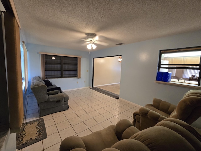 living area with visible vents, a textured ceiling, baseboards, and light tile patterned floors