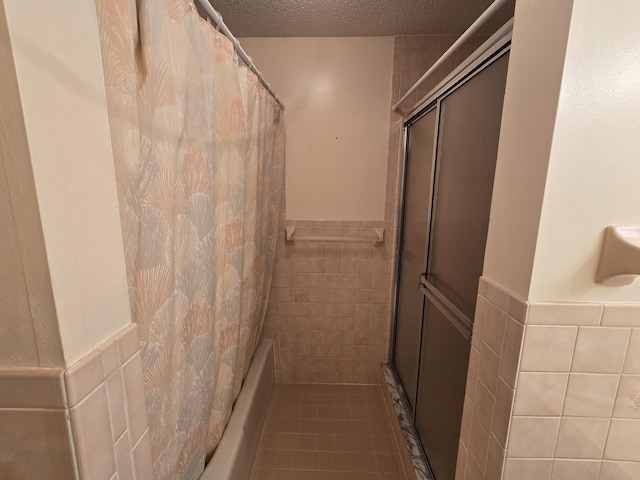 bathroom with a textured ceiling, tile walls, and a shower with shower curtain