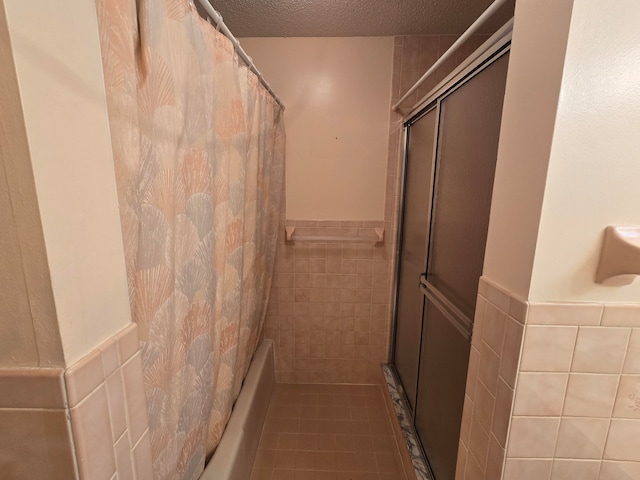 bathroom with tile patterned flooring, a shower with curtain, tile walls, and a textured ceiling