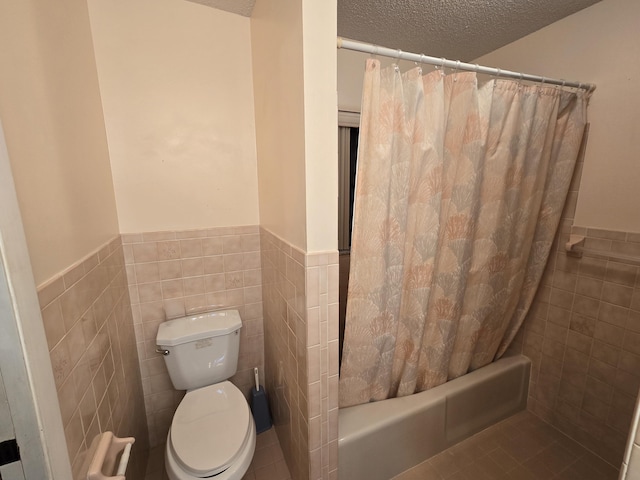 full bath featuring wainscoting, toilet, shower / bathtub combination with curtain, a textured ceiling, and tile walls