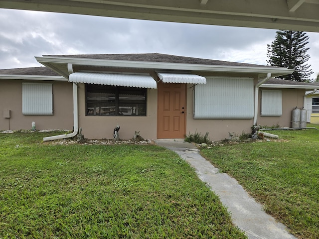 view of front of house with stucco siding and a front yard