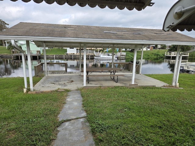 view of dock featuring a water view, a lawn, boat lift, and a patio