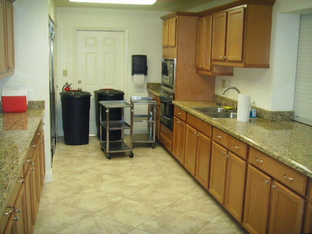 kitchen with light stone countertops, light tile patterned floors, oven, and sink