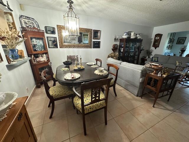 dining space with a chandelier, a textured ceiling, and light tile patterned flooring