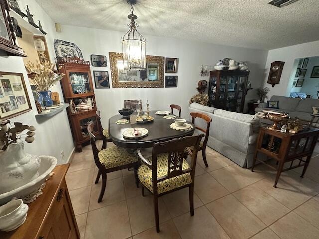 tiled dining space featuring a textured ceiling and an inviting chandelier