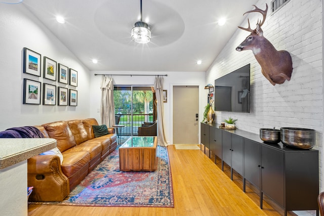 living room with ceiling fan, lofted ceiling, and hardwood / wood-style flooring